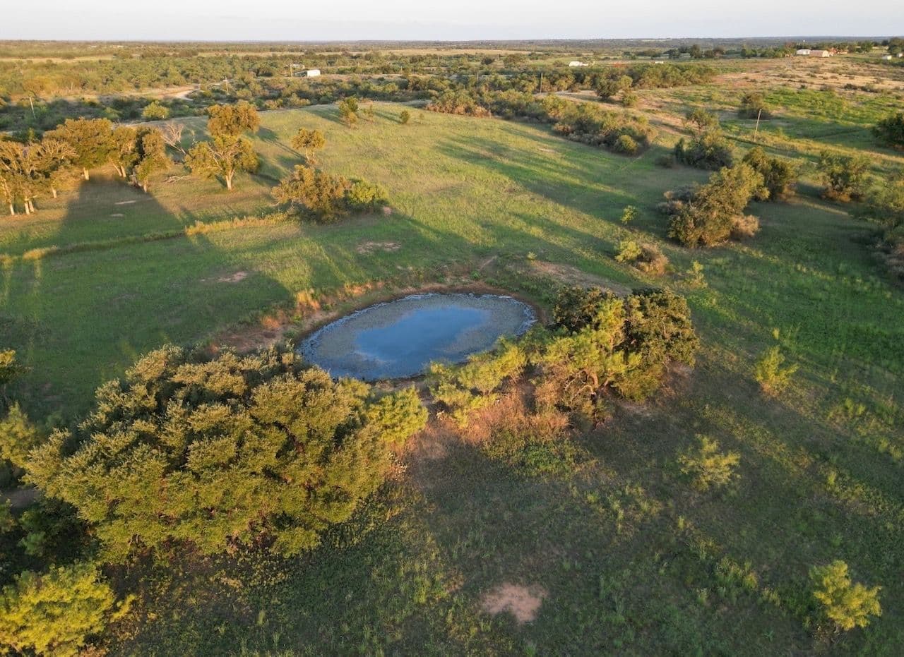Aerial land view with tank, trees and acreage
